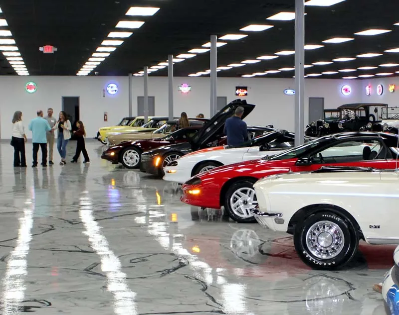 Visitors walking among rows of automobiles in the museum