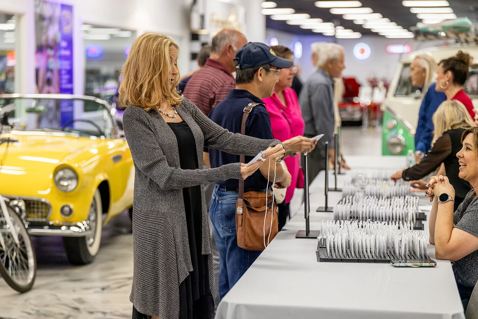 Guests moving through a buffet line beside a yellow Thunderbird on the museum floor