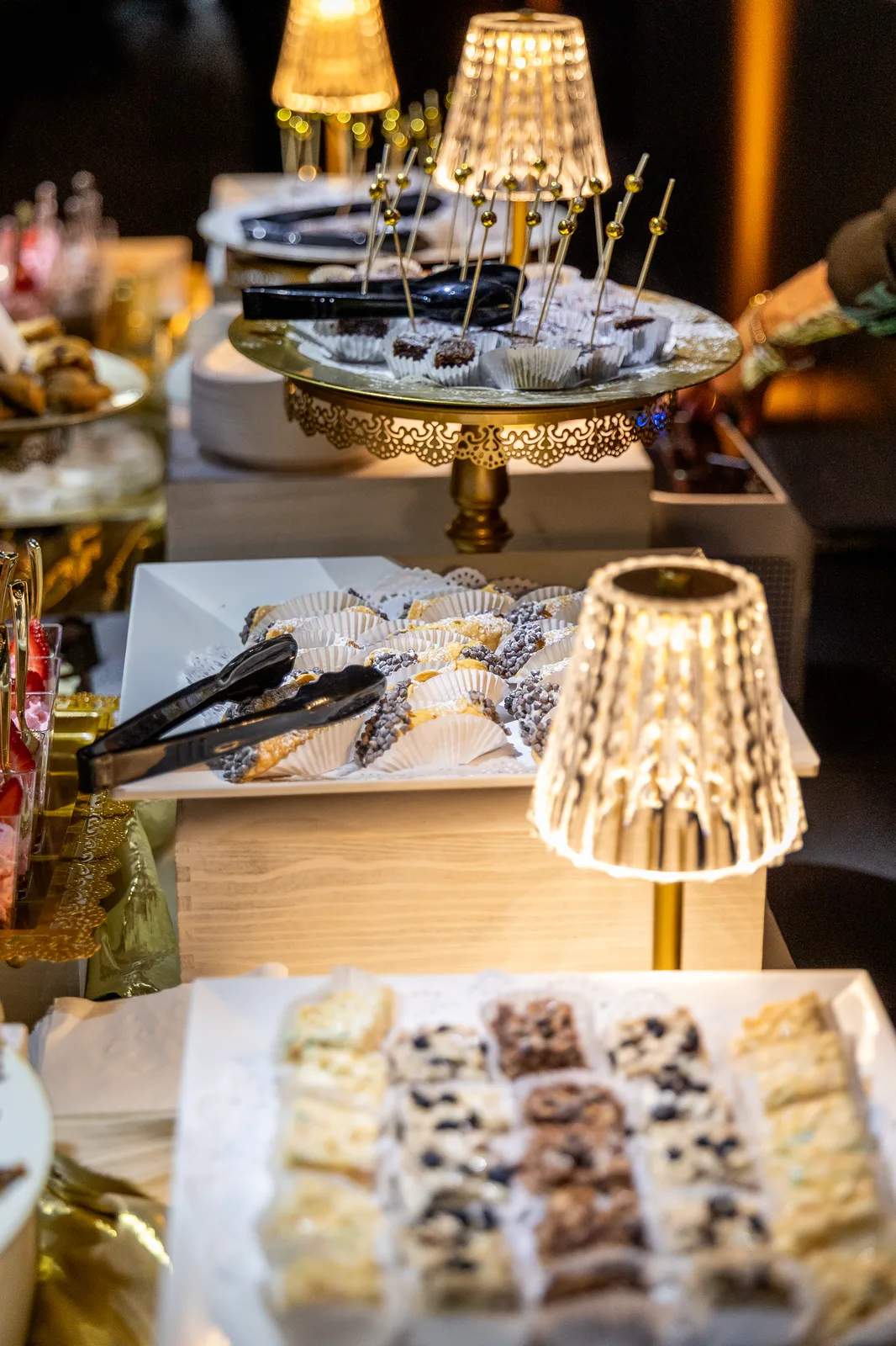 A dessert tray under a small lamp on the buffet