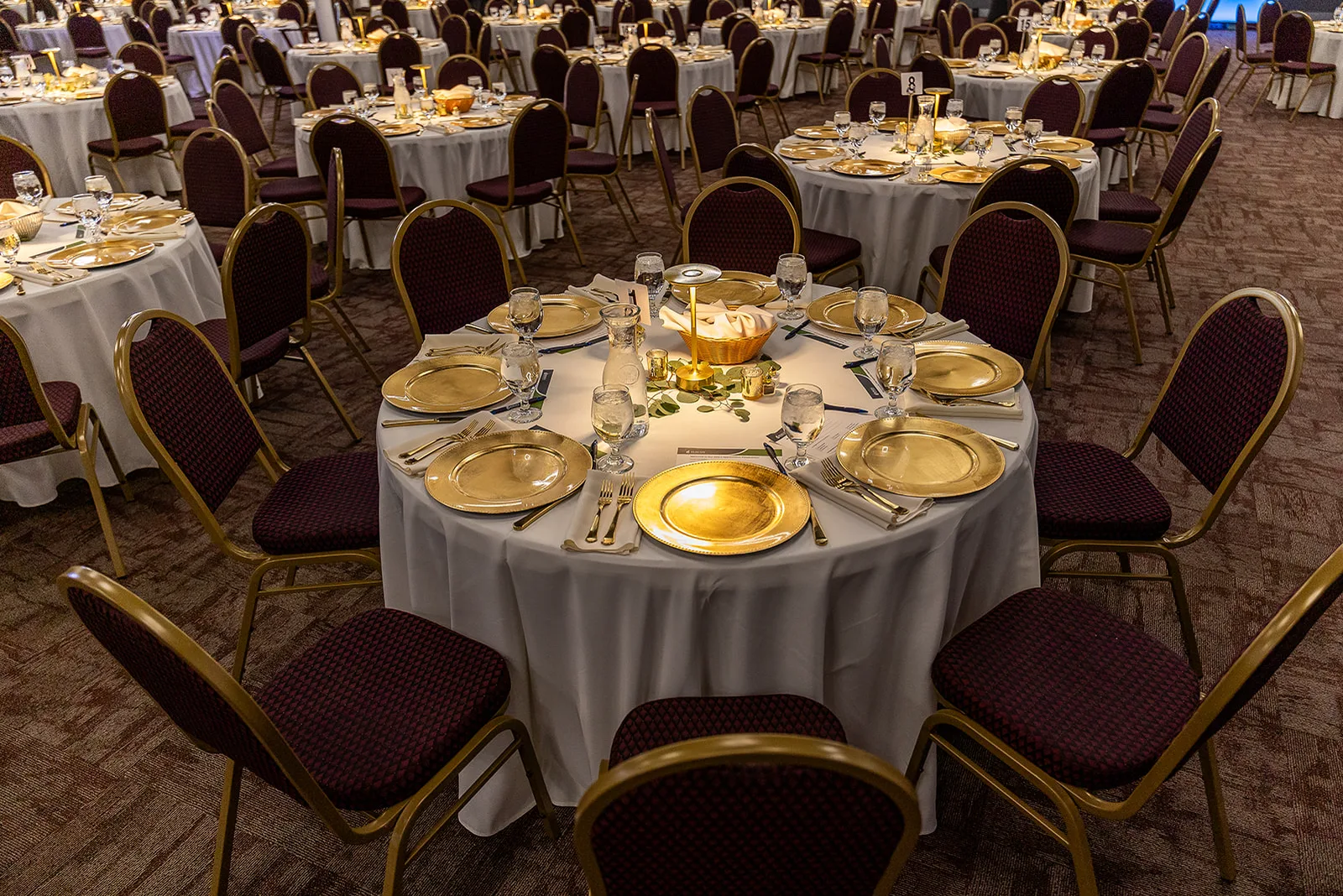 Gold charger plates and glassware on a white tablecloth